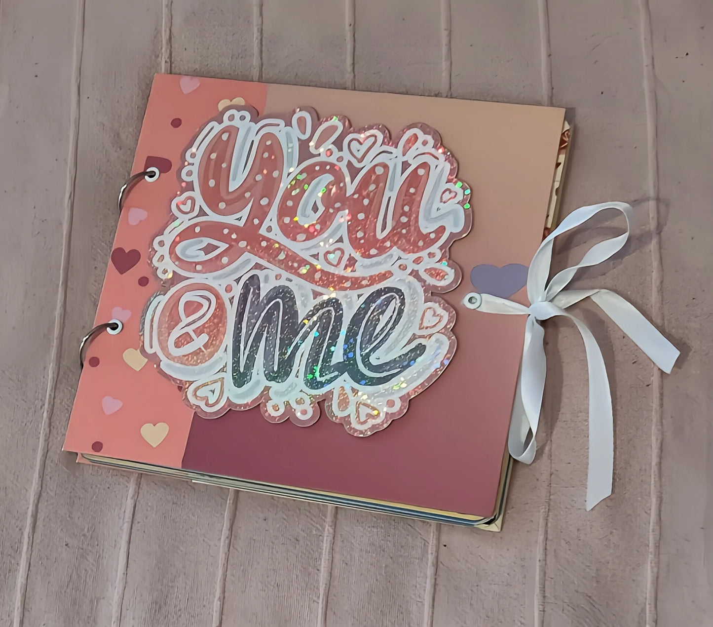 Handmade scrapbook album with 'You & me' glitter cover, heart designs, and ribbon bow