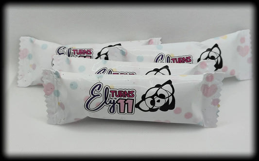 Birthday candy wrappers with 'Ely Turns 11' and cartoon raccoon, pastel polka dot design