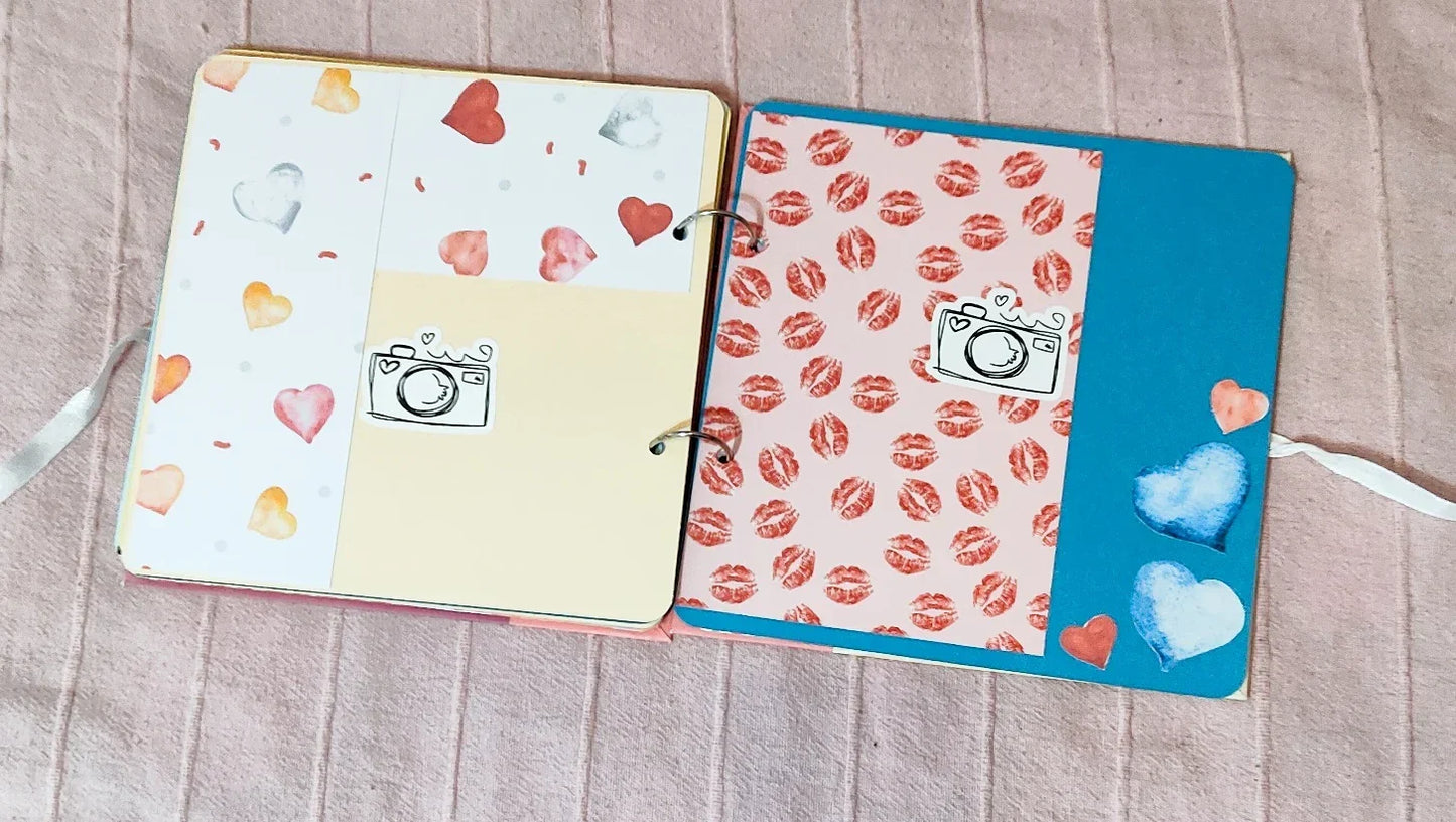 Cute scrapbook pages with heart patterns, camera stickers, and lipstick prints on soft fabric background
