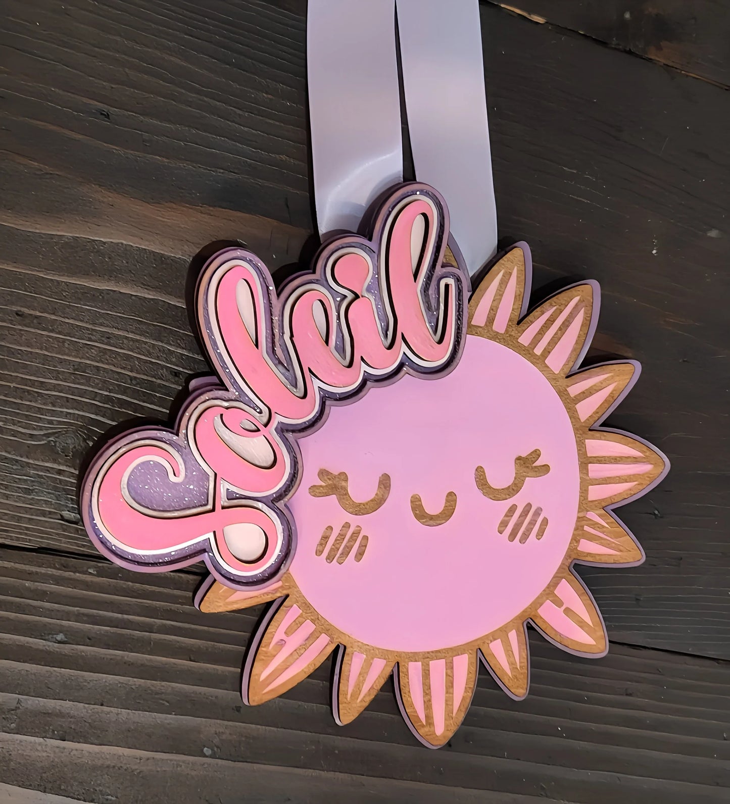 Cute pink sun wall decor with 'Soleil' text, smiling face, wood background, nursery sign