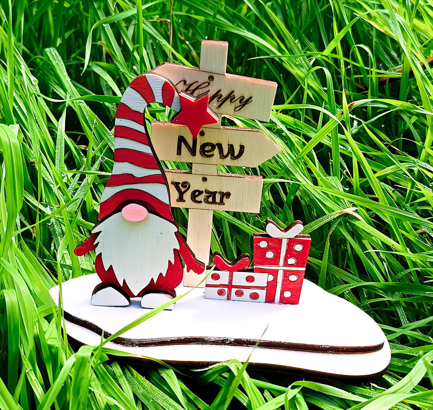 Wooden gnome with Happy New Year sign and gifts on grass, holiday decoration outdoors