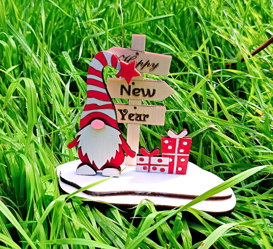 Festive gnome with Happy New Year sign and gift boxes on grass background