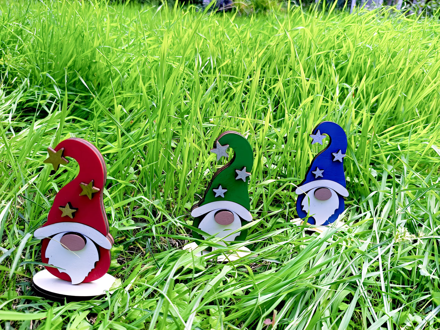 Colorful wooden gnome decorations with stars in tall green grass outdoors