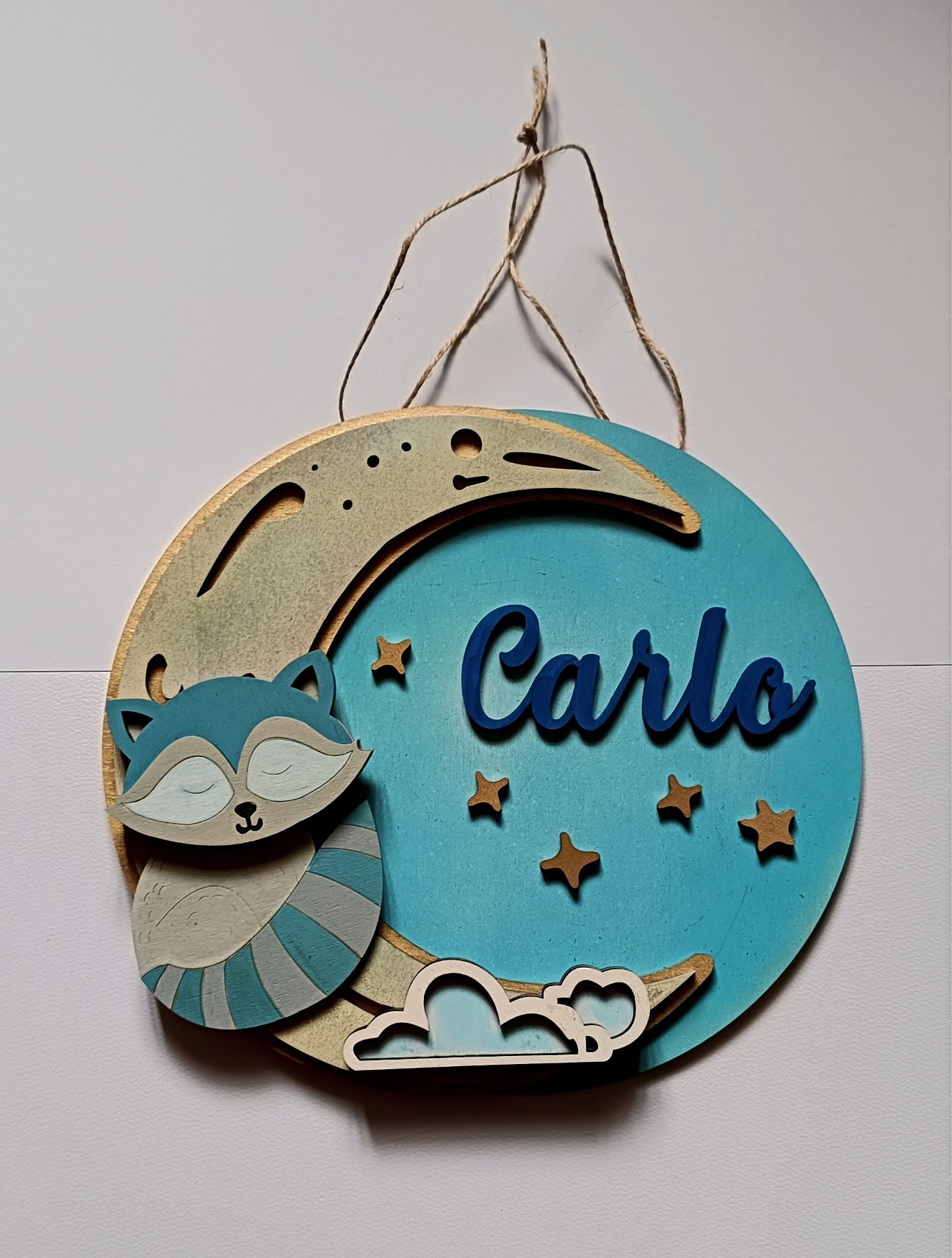 Wooden nursery wall sign with blue crescent moon, raccoon, stars, and name Carlo