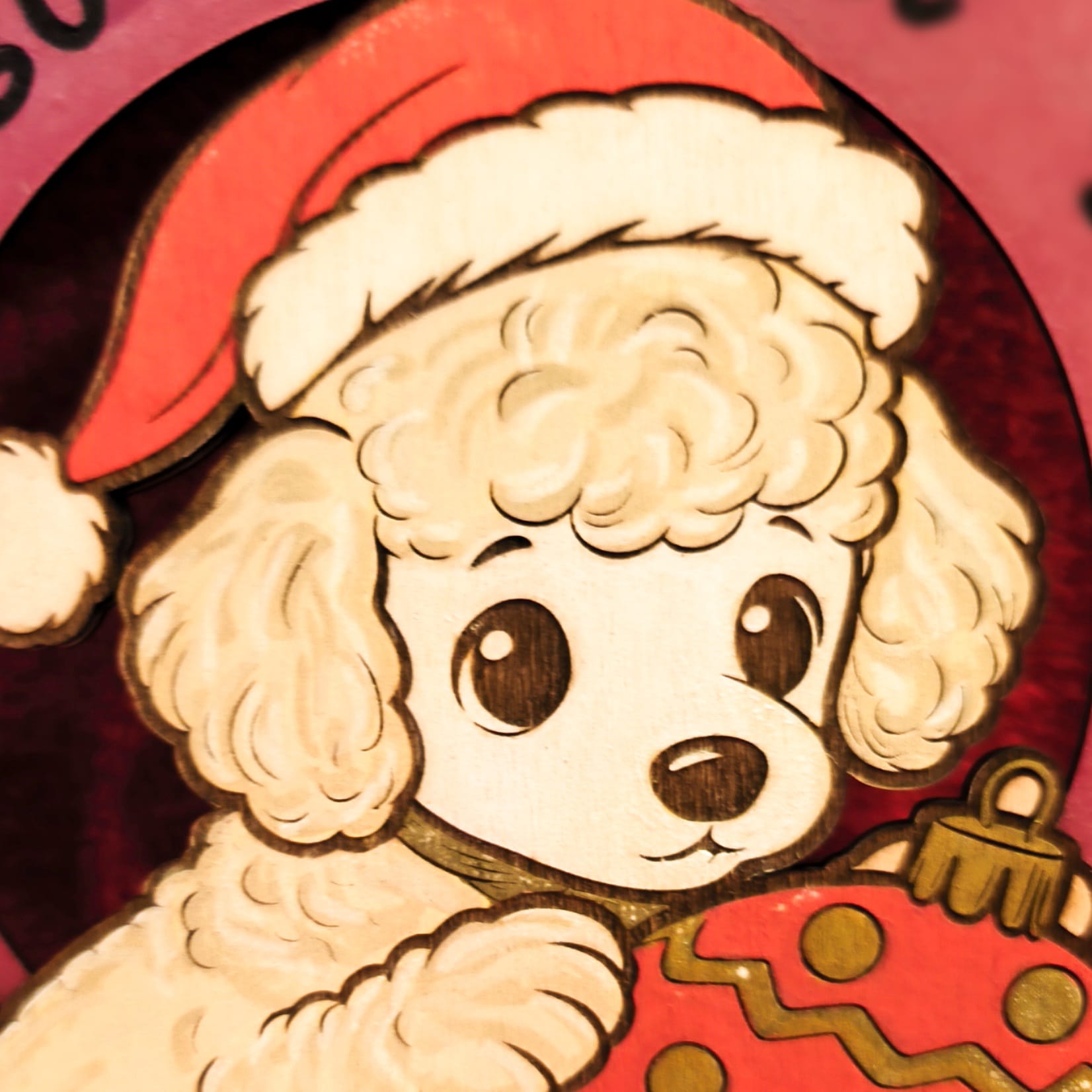 Decorazione natalizia in legno con barboncino bianco che indossa cappello di Babbo Natale e tiene un ornamento rosso decorato. Scritta Buon Natale con impronte di zampe su sfondo rosa. Addobbo artigianale fatto a mano.