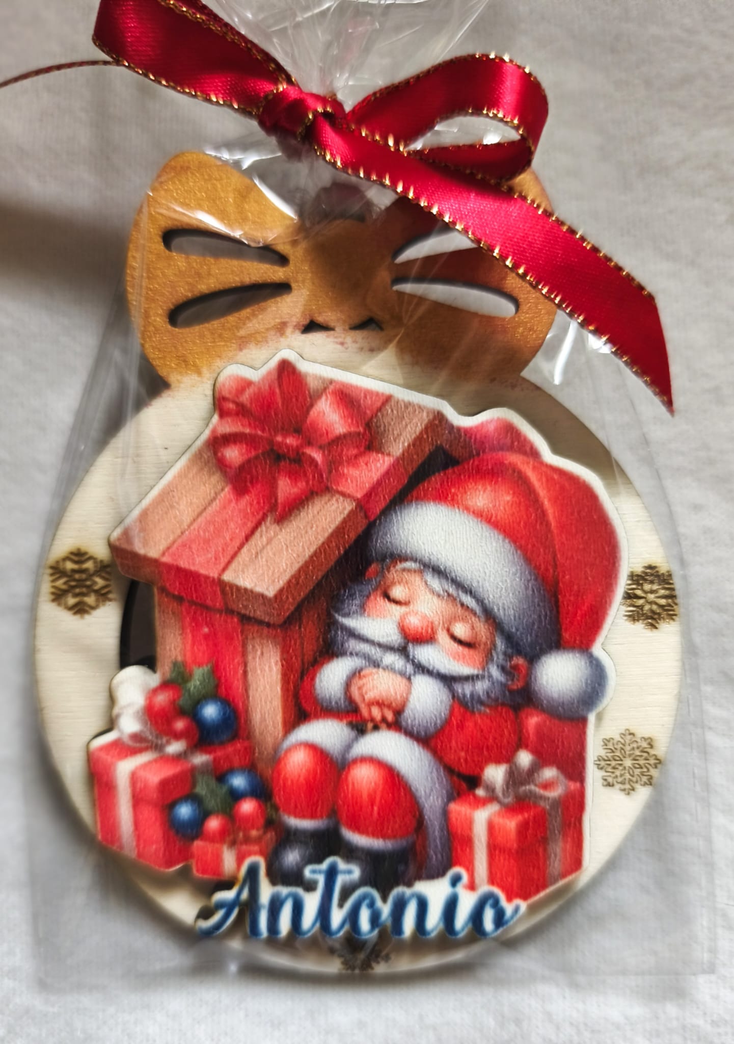 Personalized wooden Christmas ornament with a sleeping Santa, gifts, and the name Antonio