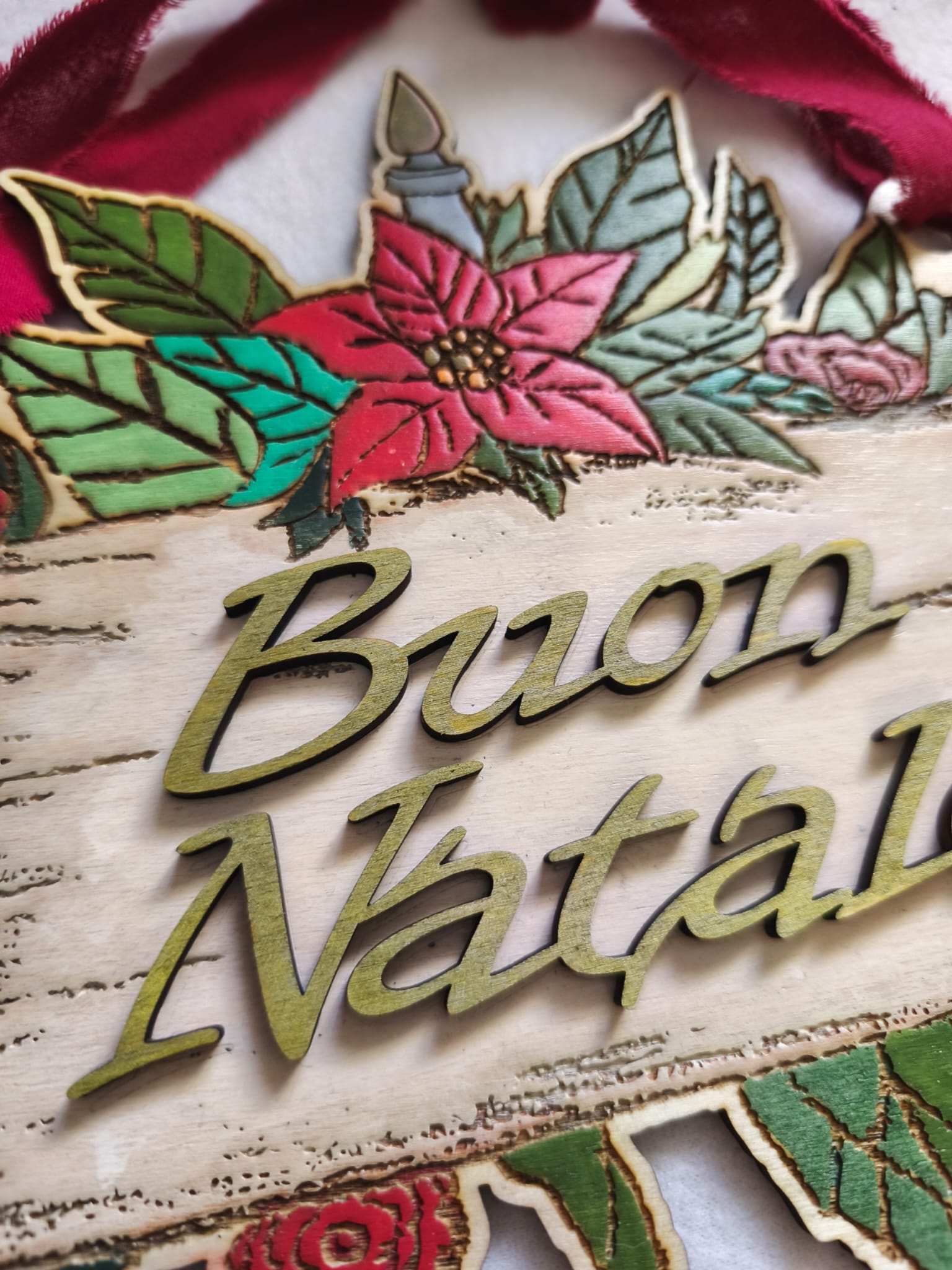 Wooden Buon Natale Christmas sign with poinsettia, green leaves, and red velvet ribbon
