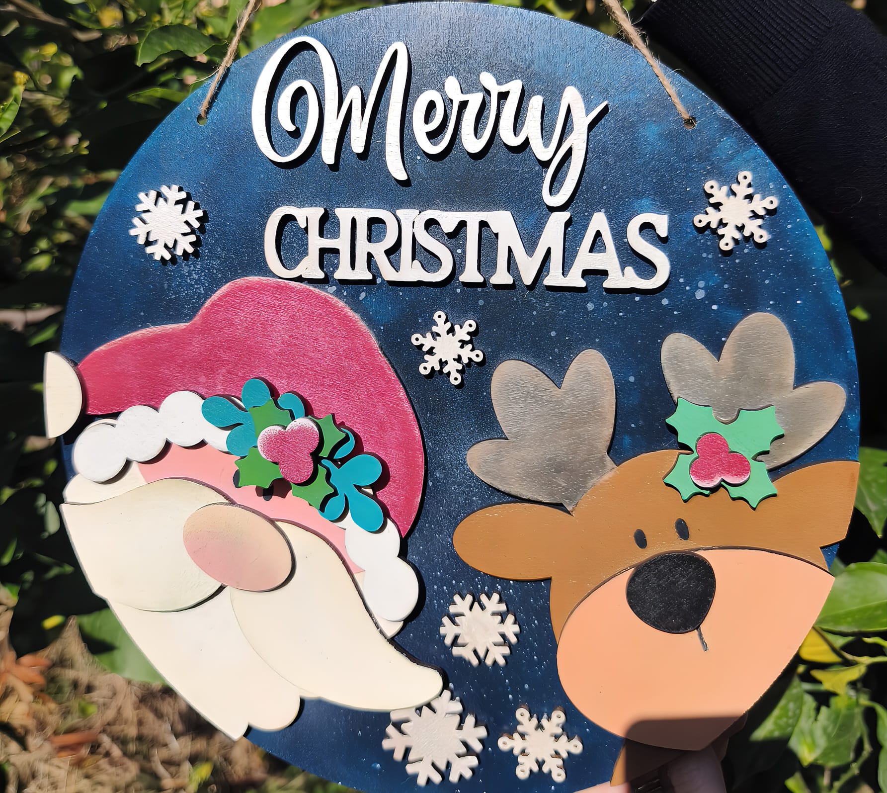 Merry Christmas sign with Santa and reindeer decorations, snowflakes, outdoor background