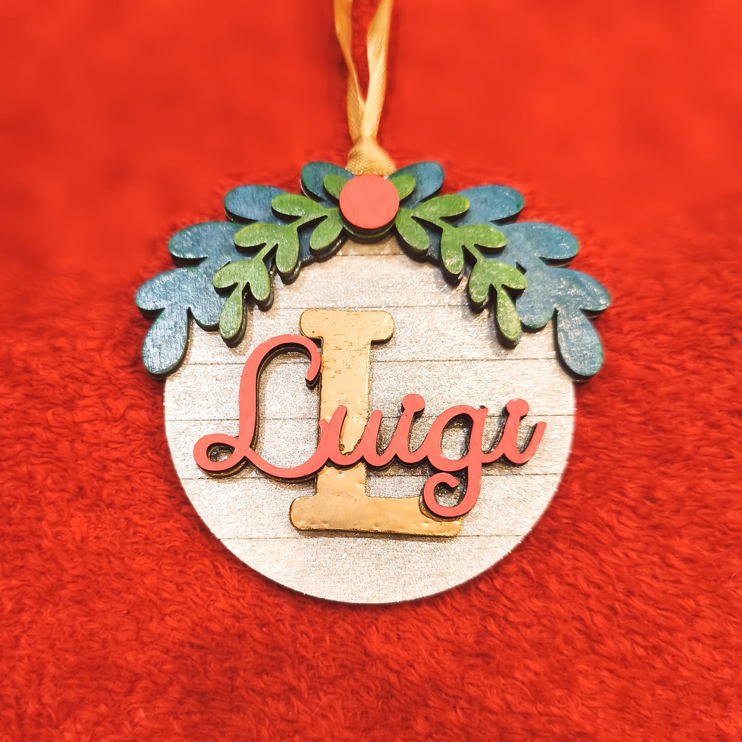 Decorazione natalizia personalizzata in legno con nome Luigi, iniziale L dorata e ghirlanda blu-verde su sfondo rosso